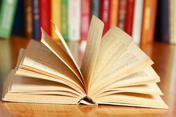 An open book lying on the desk against books