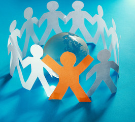 Fototapeta premium Paper people standing in a circle around glass globe isolated on