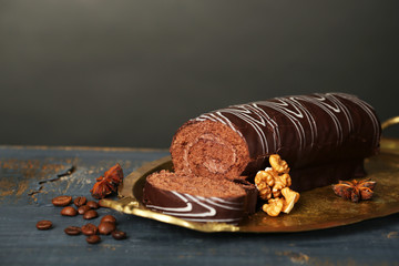 Delicious roll cake on wooden table, on dark background