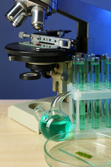 Microscope and test tubes on table, on color background