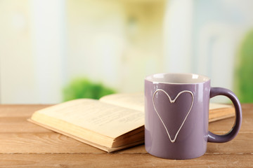 Cup of tea and book on table, on bright background