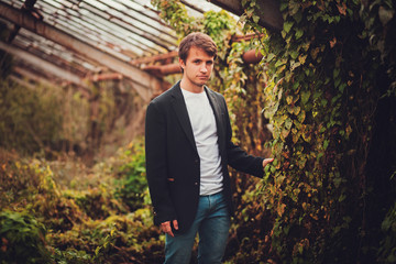 Fashionable young man in black jacket outdoor in a park