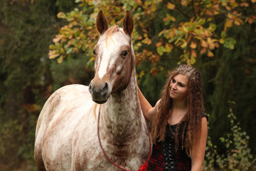 Amazing girl standing next to the appaloosa horse