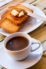 Breakfast time: cup of milky coffee, rusks and orange jam with b