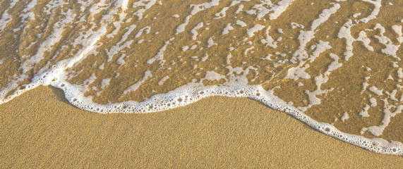 Band of sand on a sea beach with a soft wave.