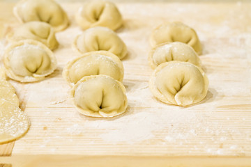 Homemade pelmeni raw dough and meat on a wooden board 