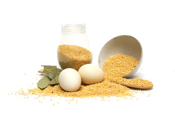 Millet in the bank, a wooden spoon, eggs and bay leaf. Photo.