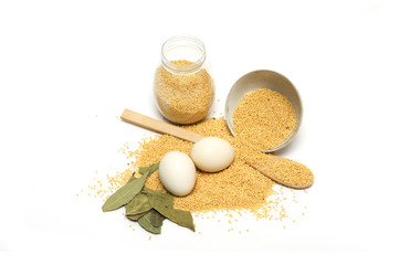 Millet in the bank, a wooden spoon, eggs and bay leaf. Photo.