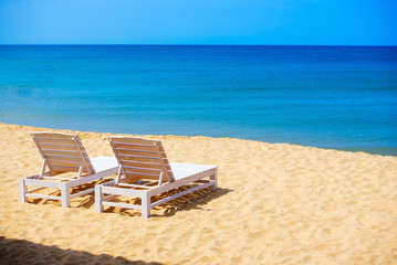 white sunbeds  on wild sea beach