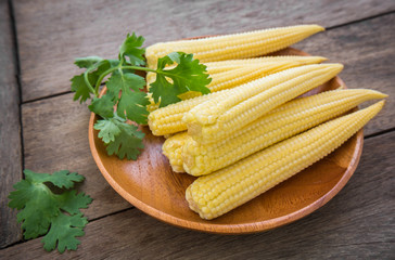 Fresh baby corn on wooden plate
