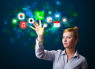 Young businesswoman pressing colorful mobile app icons with boke