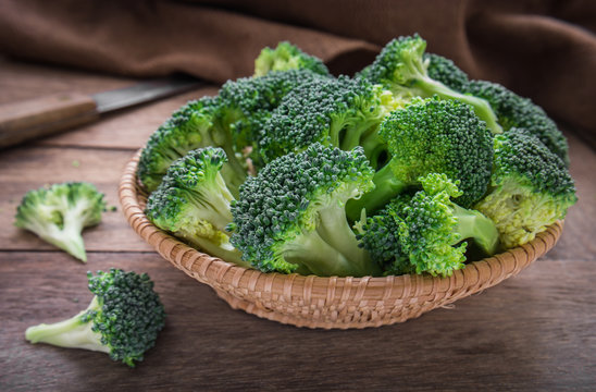 Fresh broccoli in basket on wooden table