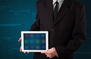 Businessman holding a white modern tablet with blurry apps