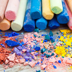 Pile of crushed chalk closeup and rainbow colored pastel crayons