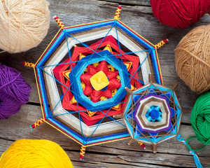 Two knitted tibetan mandala from threads and yarn on wooden rust