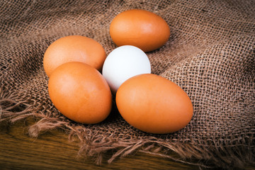 Brown and white eggs on burlap and wooden rustic table.