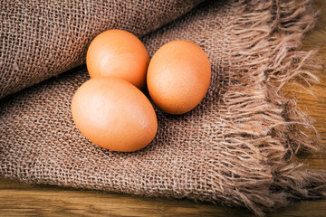 Brown eggs on burlap and wooden rustic table. Selective focus.