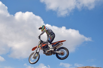 Fototapeta na wymiar Exstrim driver standing on the MX motorcycle is flying over the