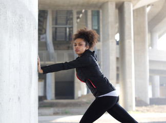 Young sports woman pushing against wall