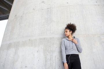 Sporty young woman standing outdoors with earphones