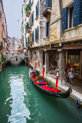 Obraz na płótnie Canvas Tourists travel on gondolas at canal