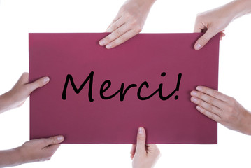 Viele Hände halten ein Plakat mit dem französischen Wort Merci