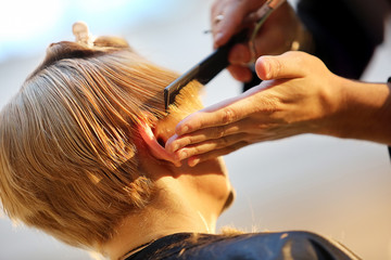 Hairdresser trimming blond hair with scissors