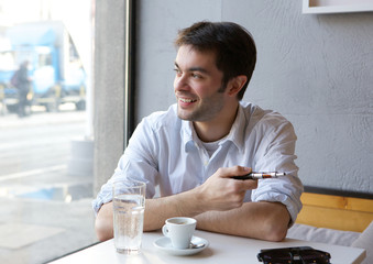 Young man smiling with electric cigarette indoors