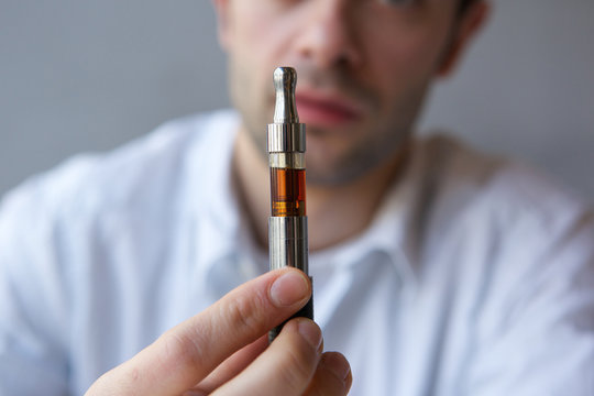 Young man showing electric cigarette close up