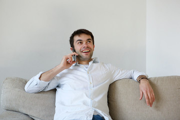 Young man relaxing at home calling by mobile phone