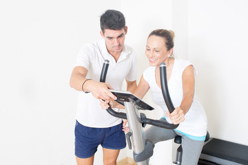 Obraz premium Coach zeigt Frau Fitnessfahrrad