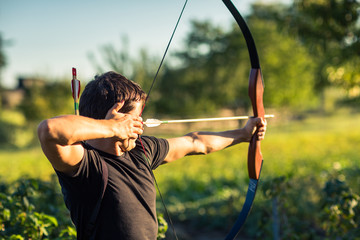 Young archer training with the  bow - obrazy, fototapety, plakaty