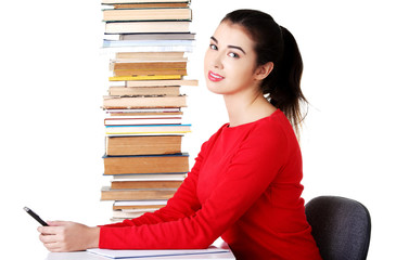 Concentrated woman sitting with stack of books