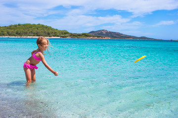Little girl playing frisbee during tropical vacation in the sea