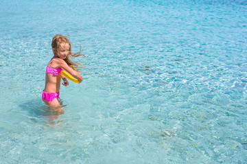 Fototapeta na wymiar Little girl playing frisbee during tropical vacation in the sea