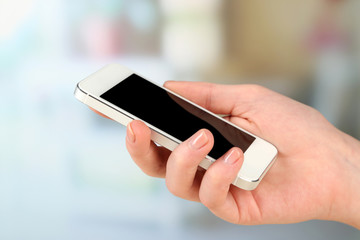 Hand using smart mobile phone on light blurred background
