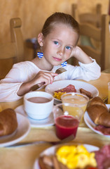 Obraz na płótnie Canvas Adorable little girl having breakfast at indoor cafe