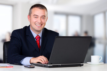Young happy businessman working in his office
