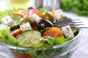 Greek salad in glass dish with fork, closeup