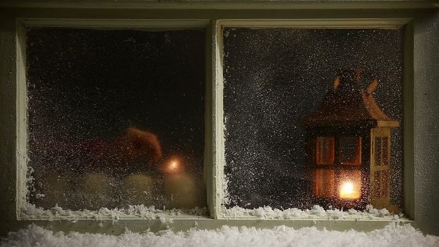 woman with matches is lightning up four candles behind a window
