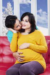 Cheerful pregnant mother kissed by her husband