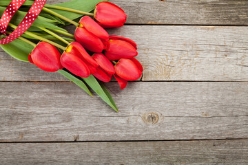 Fresh red tulips bouquet over wooden table background