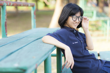 Girl wearing glasses sitting on the bench.