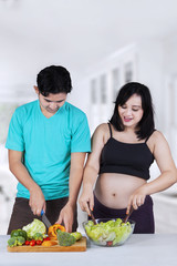 Pregnant woman in kitchen preparing salad