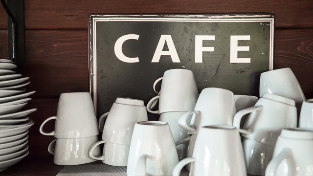 Coffee Mugs Stacks with Cafe Sign in Background 