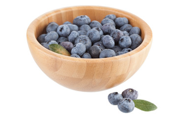 Wooden bowl with bilberry berries on a white background