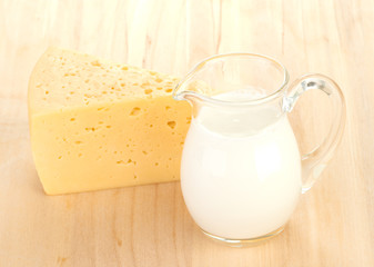Big piece of cheese, glass jug with milk