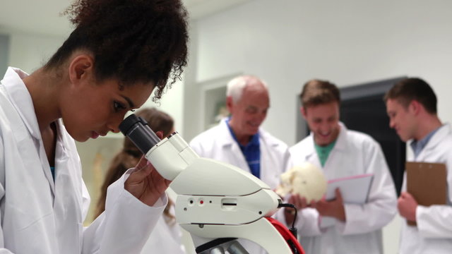 Pretty medical student looking through microscope