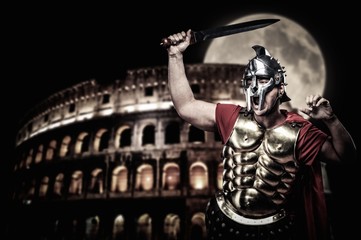 Roman legionary soldier in front of coliseum at night time