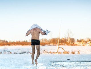 man wipes towel after swimming in  freezing hole